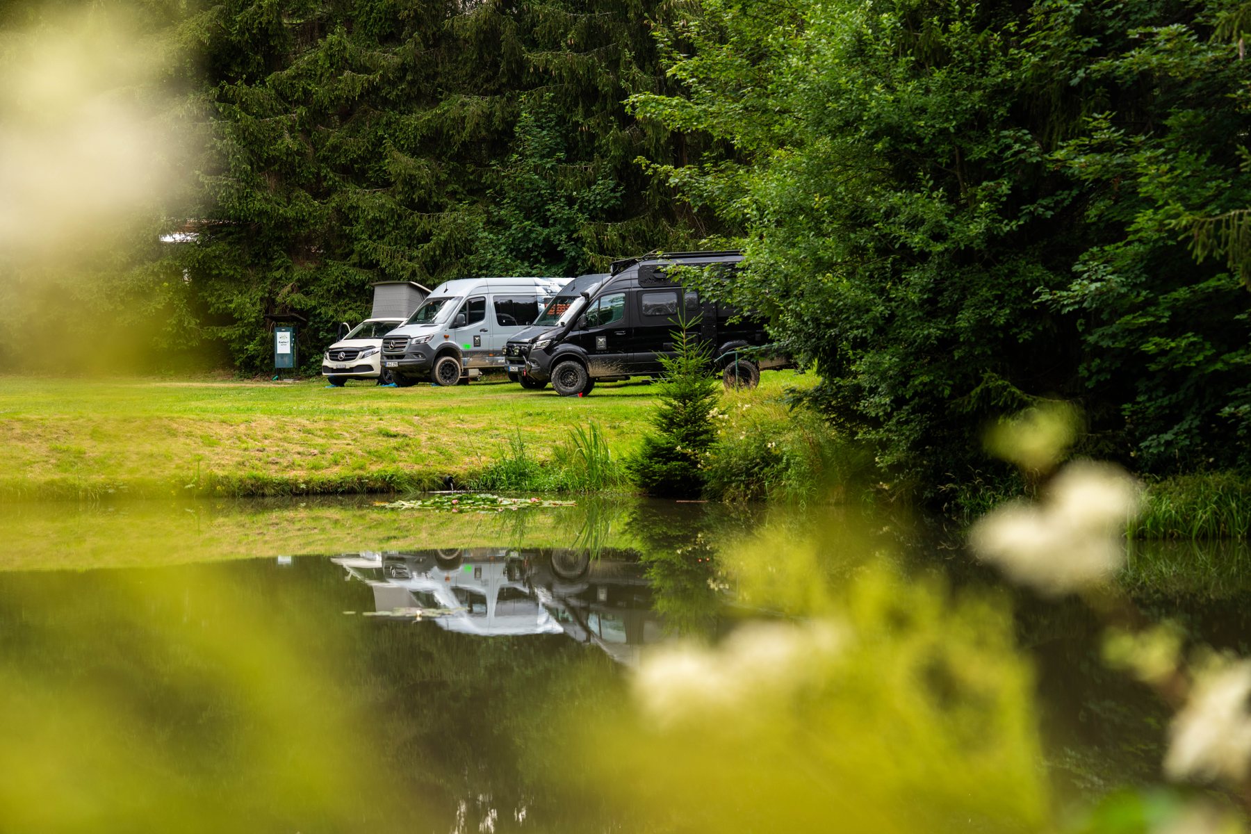 Camper auf einer Wiese neben einem Teich